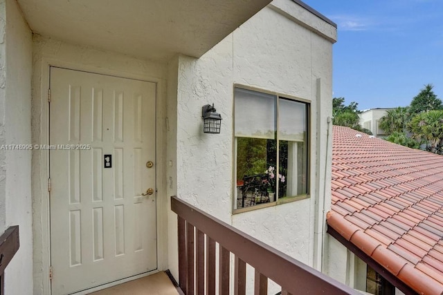 view of exterior entry with a balcony and stucco siding