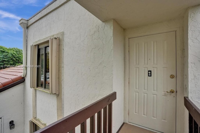 entrance to property with a balcony and stucco siding