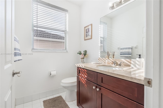 half bath featuring vanity, tile patterned flooring, toilet, and a healthy amount of sunlight