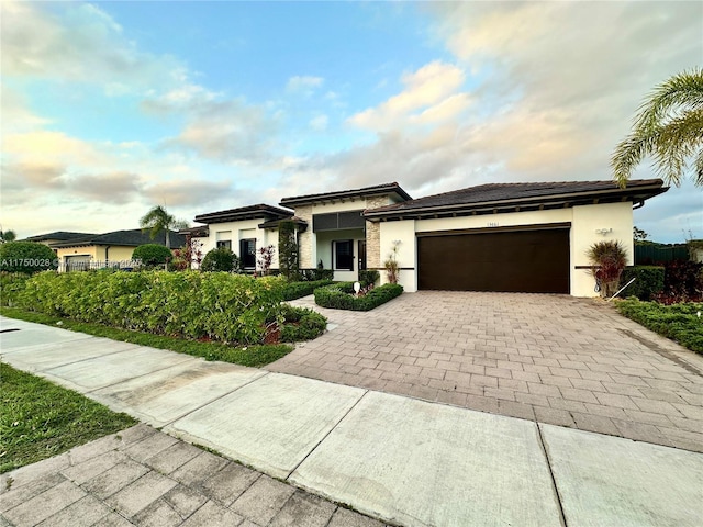 prairie-style house featuring a garage, decorative driveway, and stucco siding