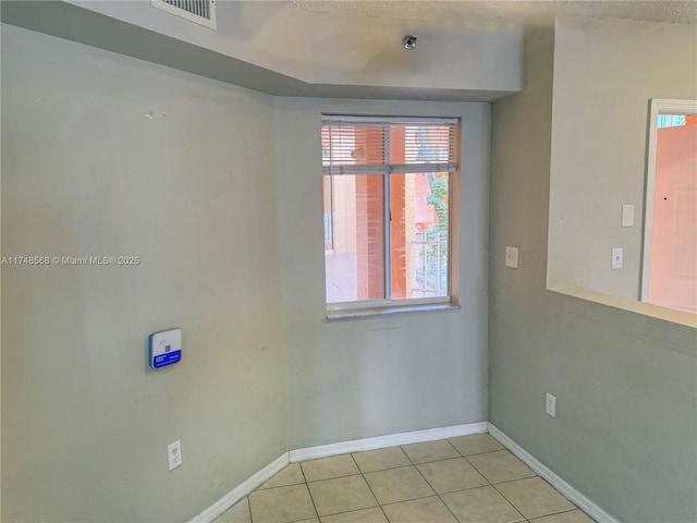 unfurnished room with light tile patterned floors, visible vents, and baseboards