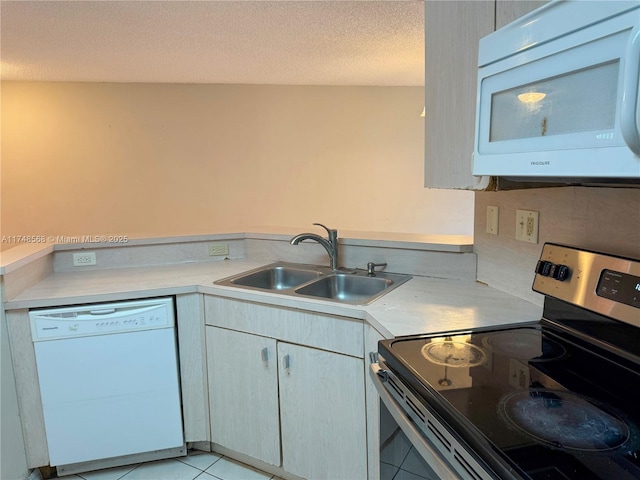 kitchen featuring light tile patterned floors, light countertops, a sink, a textured ceiling, and white appliances