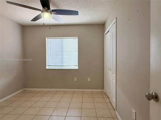 spare room with ceiling fan, a textured ceiling, baseboards, and light tile patterned floors