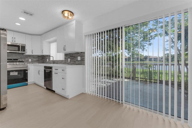 9745 NW 37th St Unit 9745, Sunrise, FL 33351 - kitchen with visible vents, white cabinetry, tasteful backsplash, light wood finished floors, and stainless steel appliances