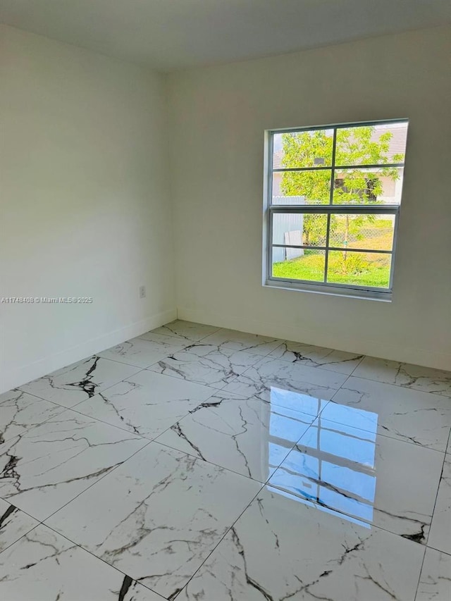 spare room with marble finish floor and baseboards