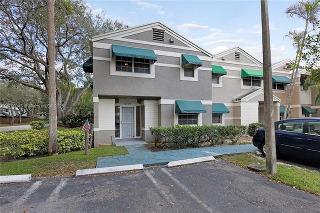 townhome / multi-family property featuring uncovered parking and stucco siding