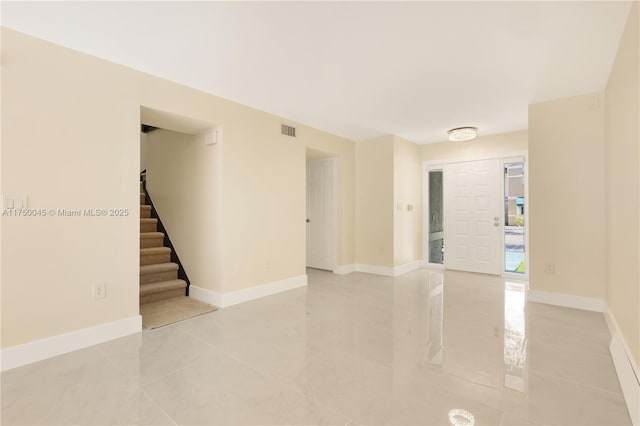 empty room with visible vents, stairway, and baseboards