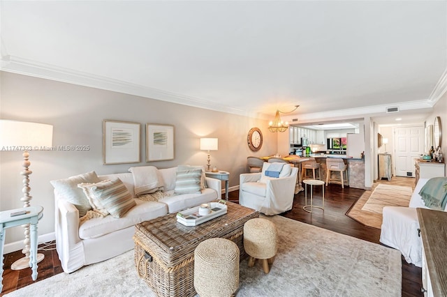 living room featuring a chandelier, wood finished floors, visible vents, baseboards, and ornamental molding