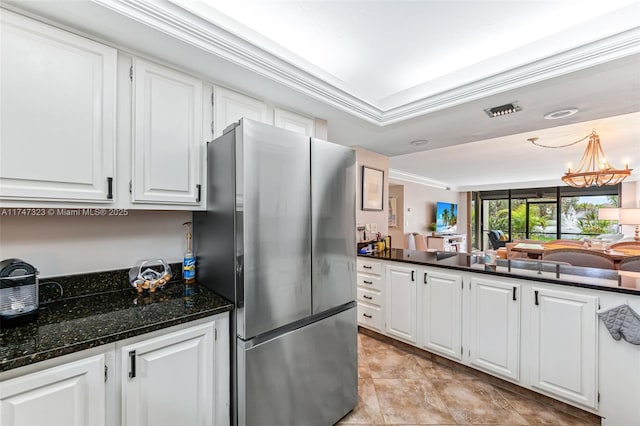 kitchen with dark stone counters, white cabinets, crown molding, and freestanding refrigerator