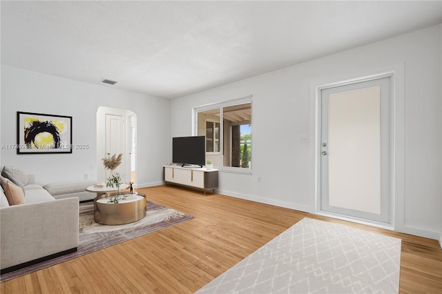 living area featuring baseboards, a textured ceiling, visible vents, and wood finished floors