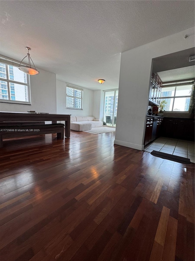 unfurnished living room featuring wood finished floors, a textured ceiling, and baseboards