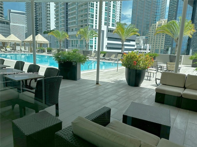 community pool featuring an outdoor hangout area, a patio, and a view of city
