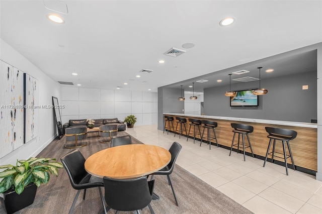 dining area featuring recessed lighting, a community bar, baseboards, and tile patterned floors