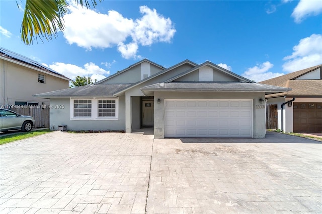 ranch-style home with decorative driveway, roof with shingles, stucco siding, fence, and a garage