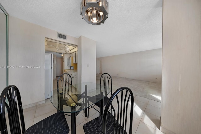 dining space featuring visible vents, light tile patterned floors, and a textured ceiling