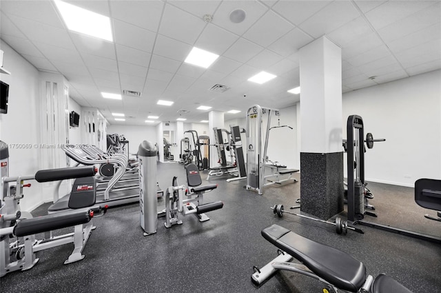 exercise room featuring a paneled ceiling, visible vents, and baseboards