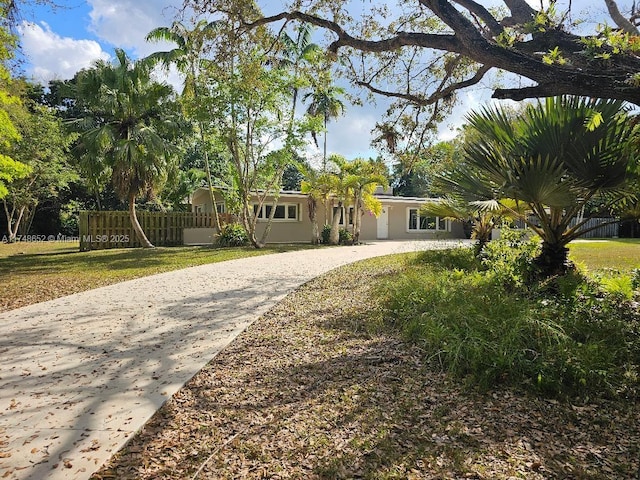 view of front of home featuring fence, a front lawn, concrete driveway, and stucco siding