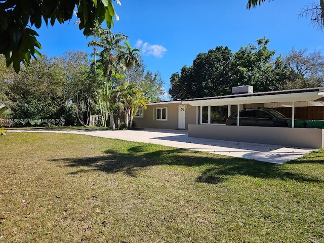 rear view of house featuring a yard and stucco siding