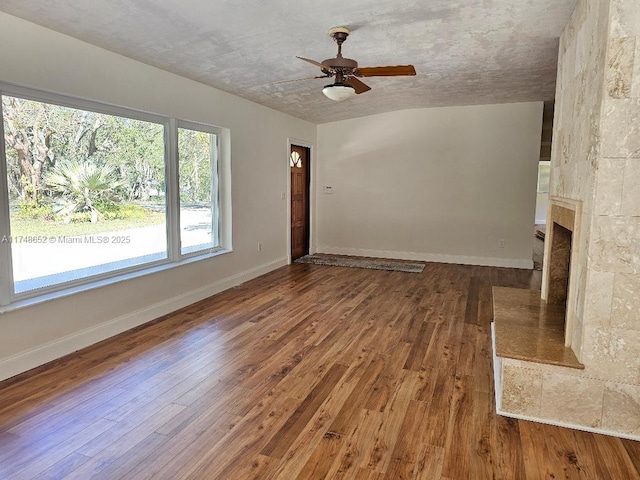 unfurnished living room featuring hardwood / wood-style flooring, baseboards, a ceiling fan, and a tile fireplace