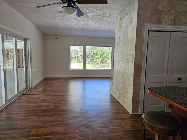 spare room with a ceiling fan, a textured ceiling, baseboards, and dark wood-style flooring