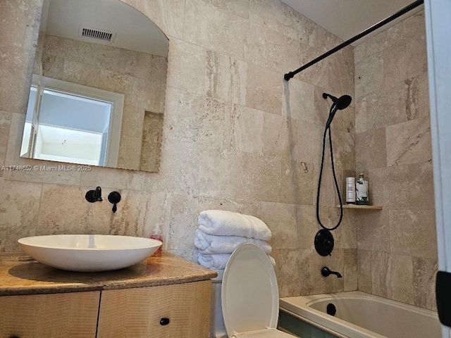 full bath with vanity, visible vents, tile walls, and bathing tub / shower combination