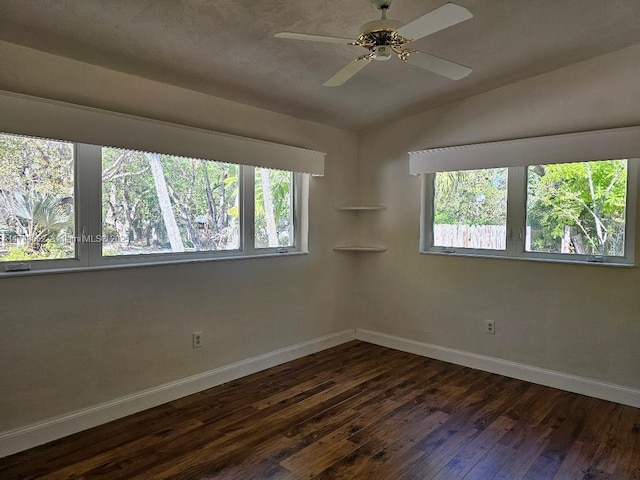 unfurnished room with vaulted ceiling, plenty of natural light, and dark wood finished floors