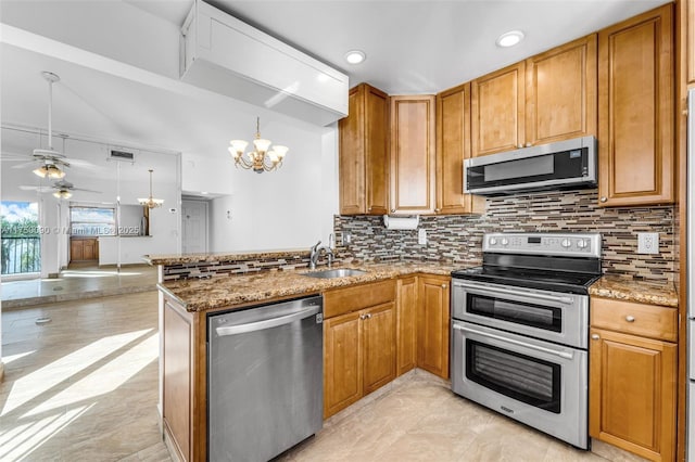 kitchen with appliances with stainless steel finishes, brown cabinets, hanging light fixtures, a peninsula, and a sink