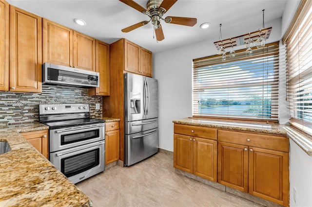 kitchen with backsplash, appliances with stainless steel finishes, light stone counters, and a wealth of natural light