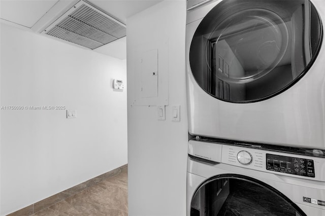 washroom with laundry area, electric panel, baseboards, visible vents, and stacked washer / drying machine