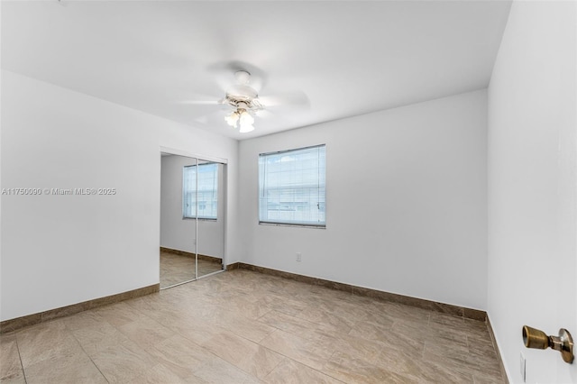 empty room featuring a ceiling fan and baseboards