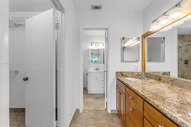 full bathroom with a walk in closet, visible vents, vanity, and tiled shower