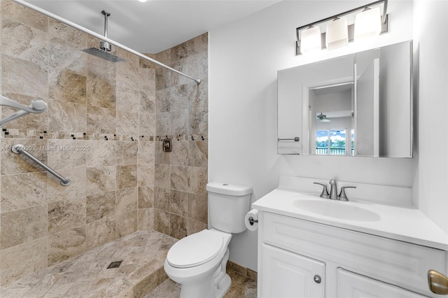 bathroom with toilet, tiled shower, and vanity