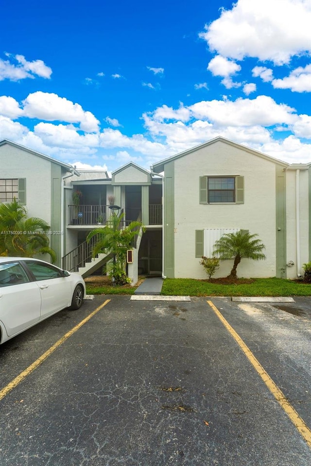 view of property featuring uncovered parking and stairway