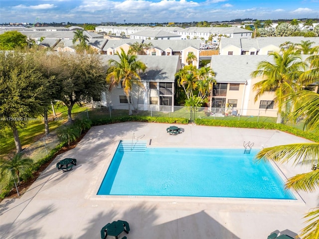 community pool featuring a residential view, a patio area, and fence