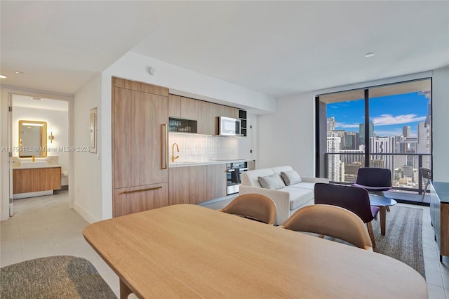 dining room featuring a wall of windows, a view of city, light tile patterned flooring, and baseboards