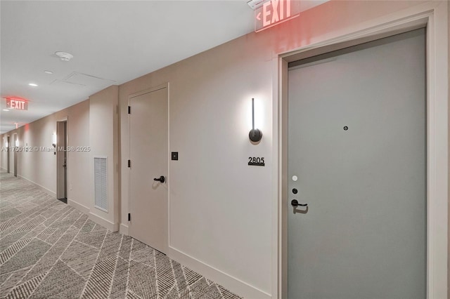 hall featuring carpet floors, visible vents, and baseboards