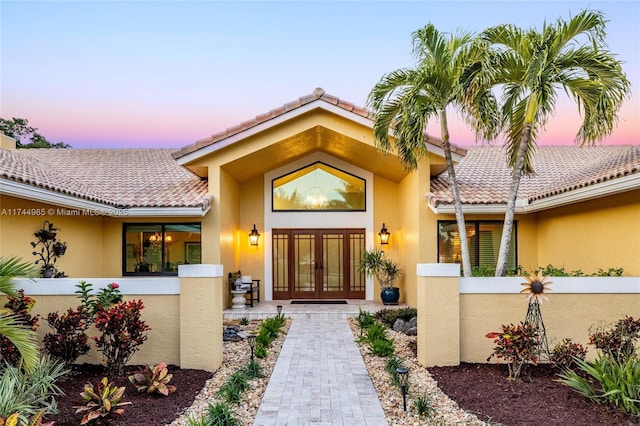 doorway to property with a tiled roof, french doors, and stucco siding