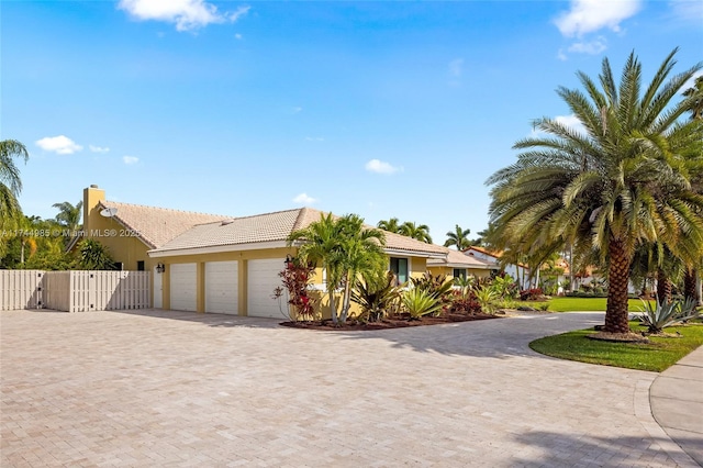 view of front of house with decorative driveway, an attached garage, fence, and stucco siding