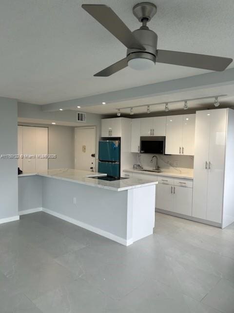 kitchen featuring refrigerator, light countertops, visible vents, backsplash, and white cabinets