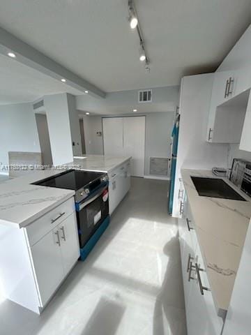 kitchen featuring light stone counters, appliances with stainless steel finishes, white cabinetry, a sink, and track lighting