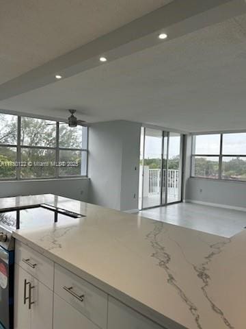 kitchen featuring light stone counters, recessed lighting, open floor plan, white cabinets, and stainless steel electric range