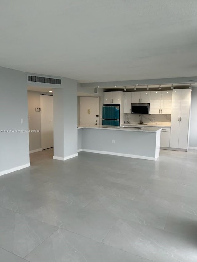 unfurnished living room featuring a sink, visible vents, and baseboards