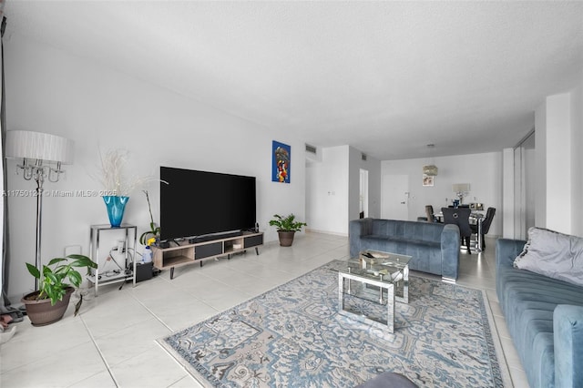 living area with tile patterned flooring, visible vents, and a textured ceiling