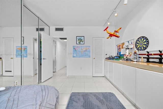 300 Bayview Dr Unit 807, Sunny Isles Beach, FL 33160 - bedroom with a textured ceiling, light tile patterned flooring, and track lighting