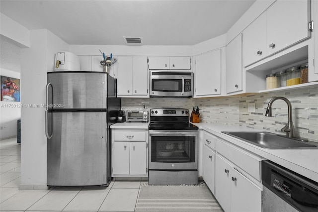 kitchen featuring light countertops, backsplash, appliances with stainless steel finishes, and a sink