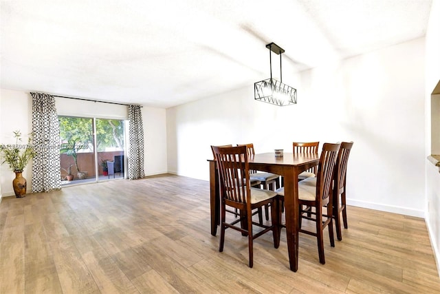 dining space with light wood finished floors, baseboards, and an inviting chandelier