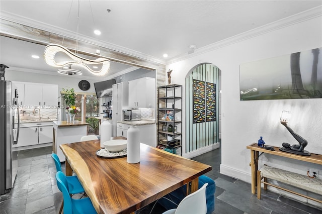 dining room with arched walkways, crown molding, baseboards, and recessed lighting