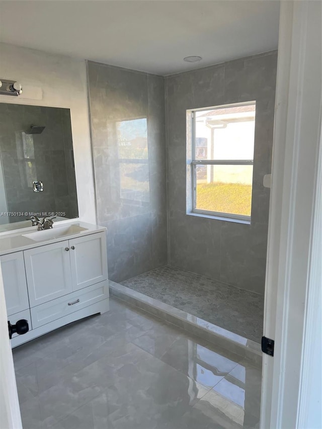 full bathroom featuring a tile shower and vanity