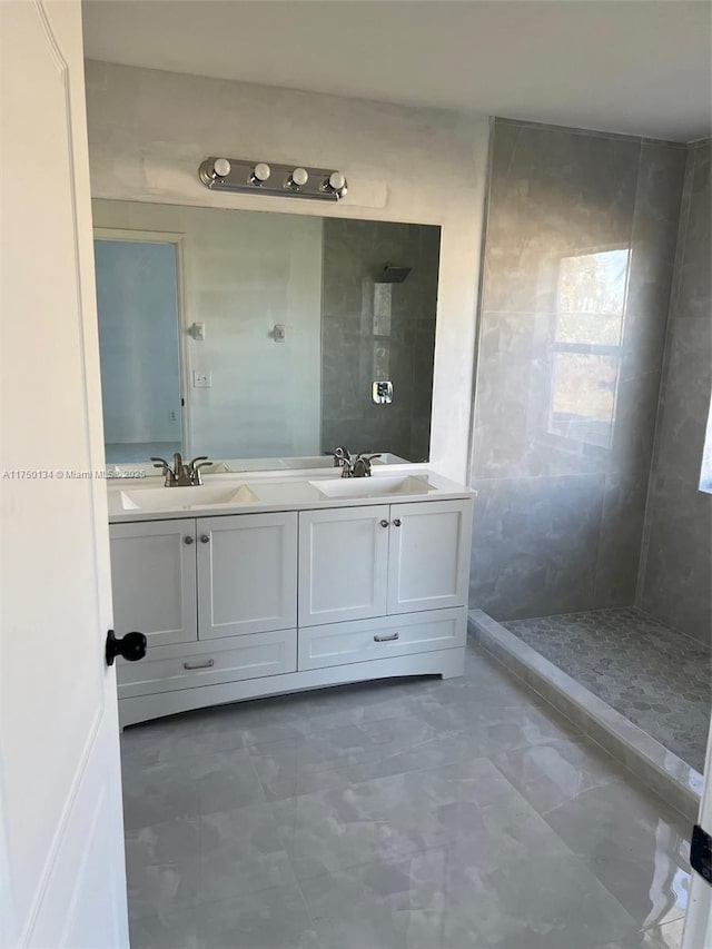 bathroom with tiled shower, a sink, and double vanity