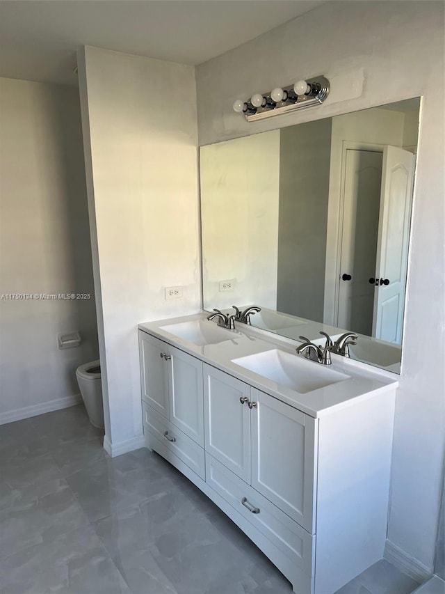 full bath featuring baseboards, a sink, toilet, and double vanity